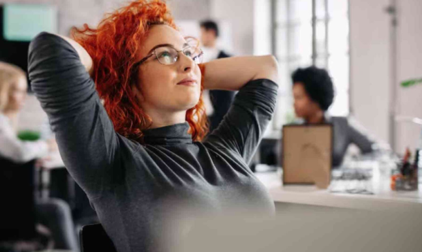 Woman With Curly Bright Red Hair Relaxing in a Chair in an Office